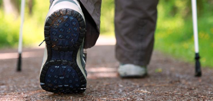 Nahaufnahme eines Wanderschuhs mit abgenutzter Sohle auf einem naturbelassenen Waldweg.